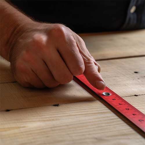 a person measuring with a tool on wood